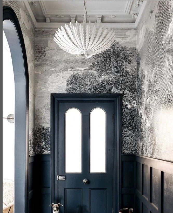 Narrow hallway with decorative wallpaper, a chandelier, and a dark blue door.