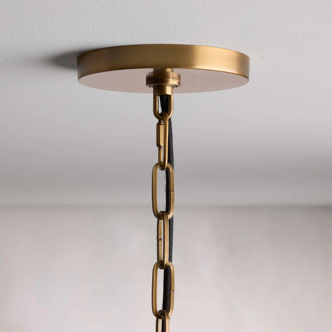 Melton Pendant Light – a striking blend of smooth brass and textured linen fabric, featuring industrial-inspired brass arms and flared shades, elegantly accented with brass detailing at the base.