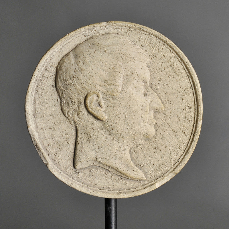 19th-Century Stucco Collector's Medallions – artist-crafted commemorative pieces, displayed on matte black metal stands, honoring past exhibitions and events.