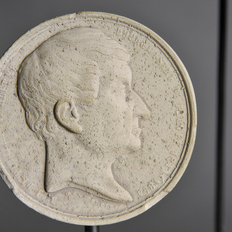19th-Century Stucco Collector's Medallions – artist-crafted commemorative pieces, displayed on matte black metal stands, honoring past exhibitions and events.